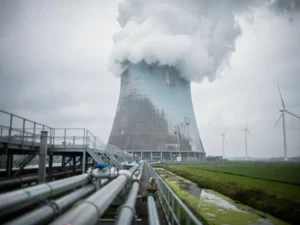 Industriële koeltoren van een datacenter stoot waterwalm uit boven Nederlands polderlandschap met windturbines op de achtergrond.
