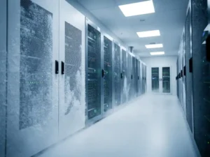 Serverrekken in een koele datacentergang met bevroren ventilatiepanelen, condensatienevel en staalblauwe verlichting.